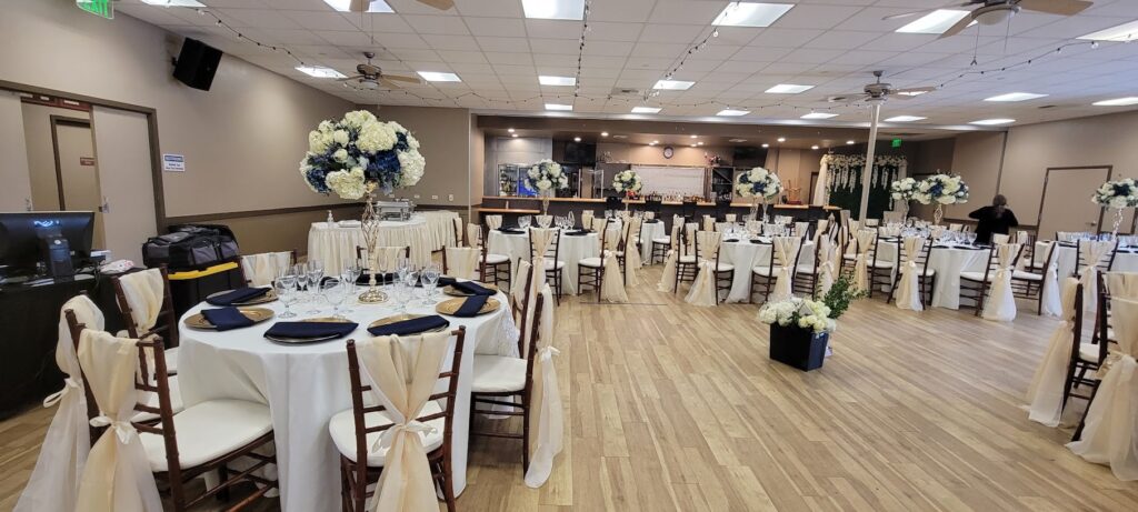 Banquet hall with round tables, white chair covers and floral decorations prepared for a special event.